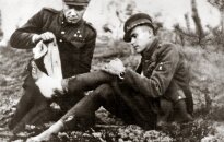 Dainavos apygardos partizanas Feliksas Daugirdas-Šarūnas bintuoja koją bendražygiui Vincui Kalantai-Nemunui. Apie 1949 m.