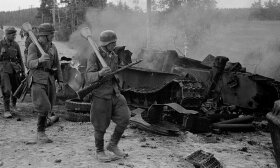 Suomių kariai eina pro pamuštą sovietų tanką 
